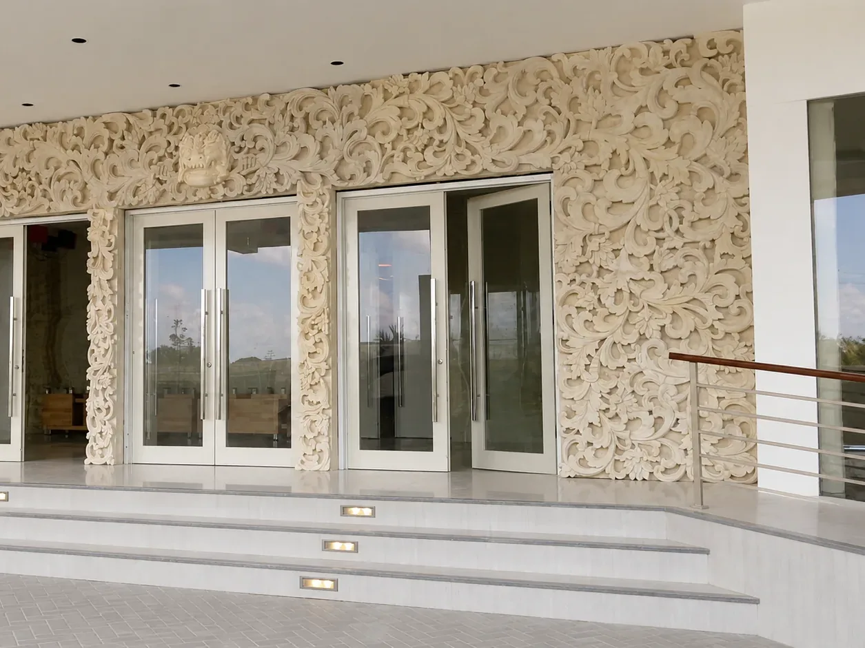 Close view of the scrolling botanical relief beside the entrance doors