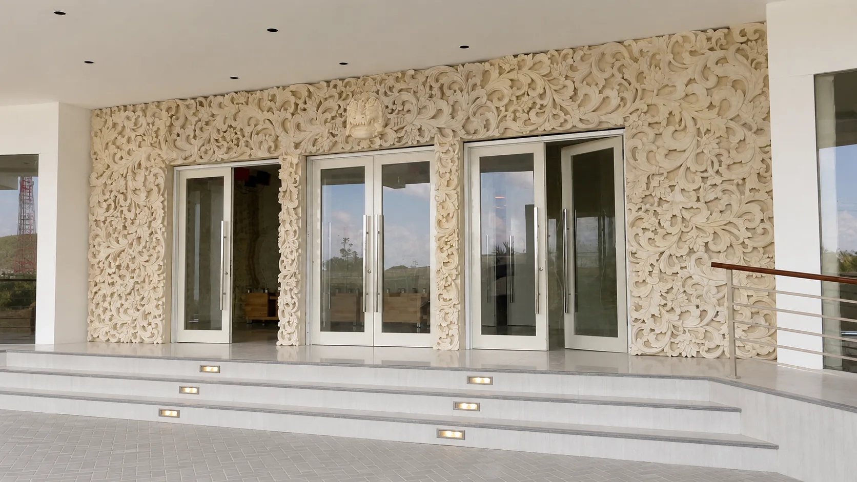 Modern entrance facade wrapped in dense botanical stone carving