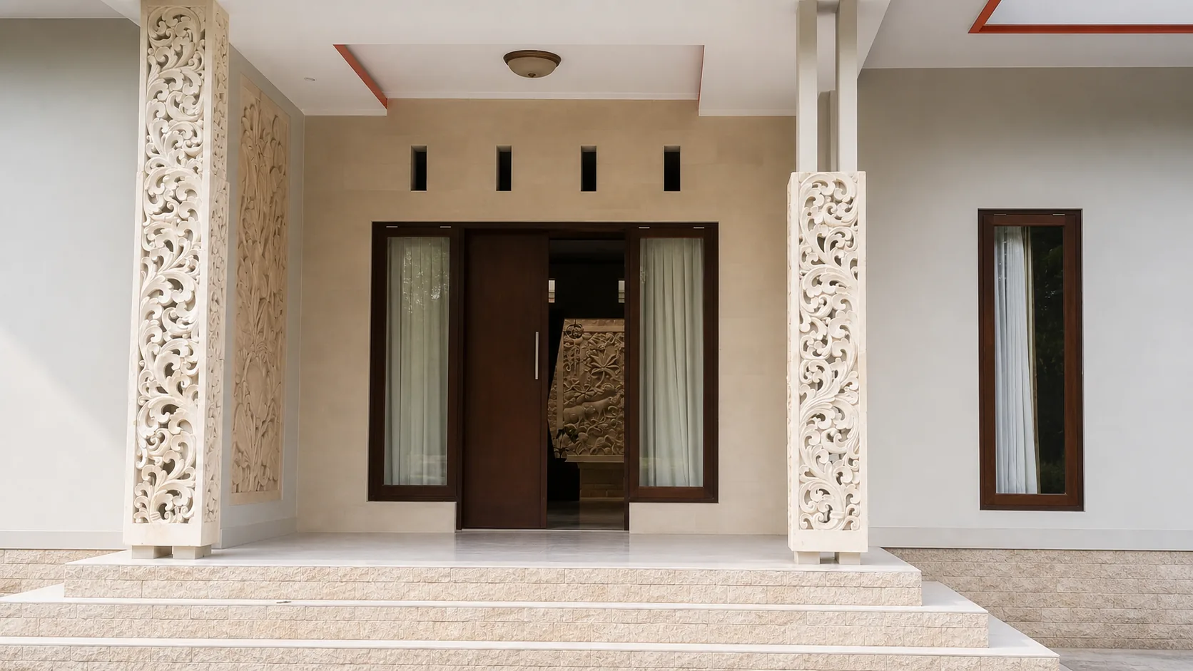 Completed residential entrance framed by carved stone columns